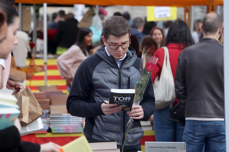 A passerby checks a book at one of the many stalls installed in Girona for Sant Jordi